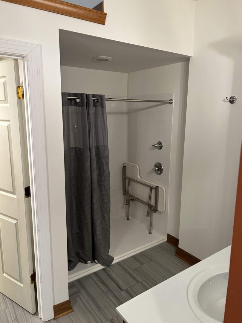 Accessible shower with a gray curtain and grab bars in a clean bathroom.
